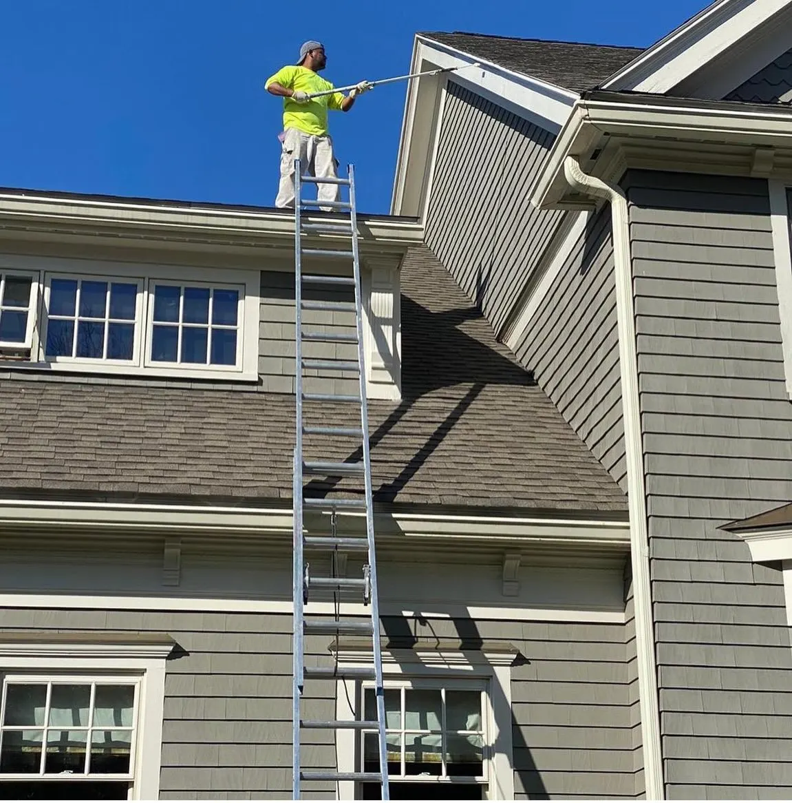 Painter on a ladder working on exterior trim